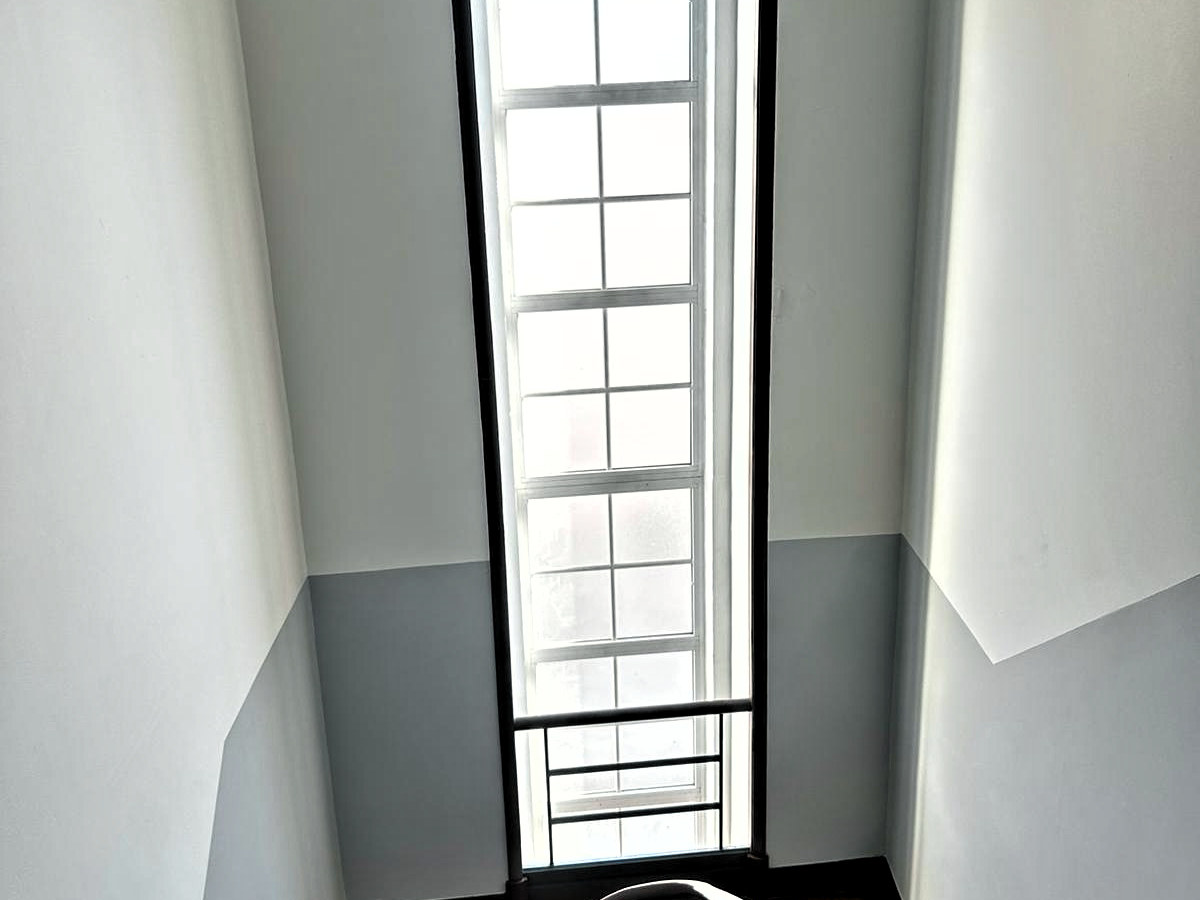 Parede do vão de escada depois de pintada: branco em cima, barra cinzenta em baixo e o aro da janela em castanho