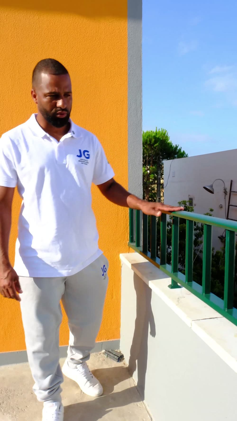 Gleidison, da JG Pinturas, junto à guarda verde de um terraço com parede exterior pintada de laranja