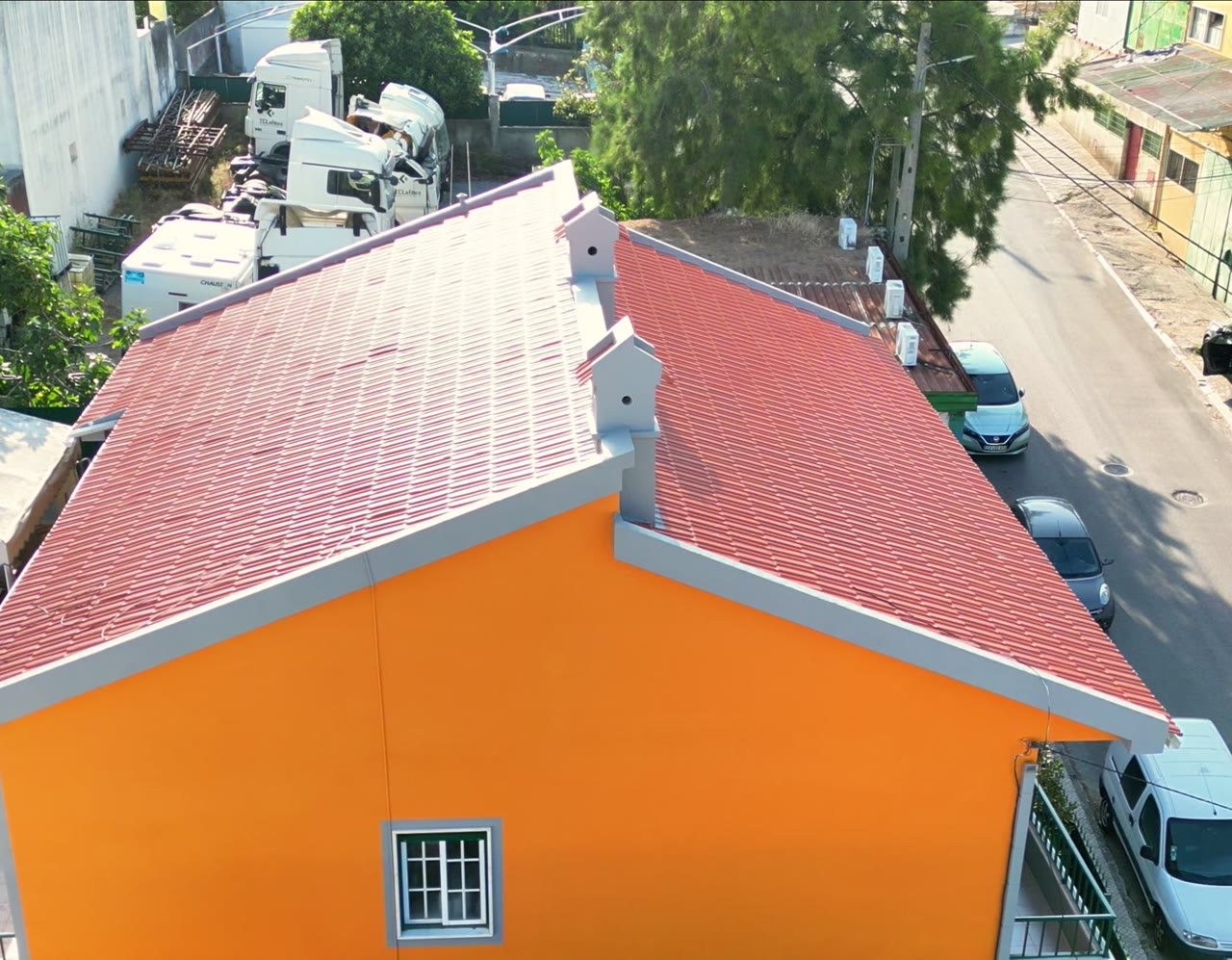 Moradia com fachada laranja renovada e telhado cerâmico tratado, vista aérea de uma obra exterior da JG Pinturas